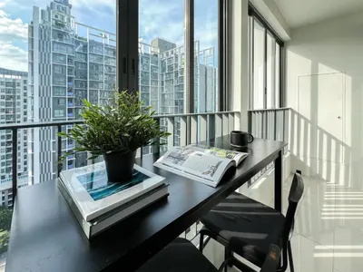 a table with a book and a plant on a balcony at Tranquil Apt 2 BR - Ultra Fast Wifi - BTS On Nut in Bangkok