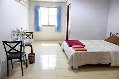 a bedroom with a bed and a table and a window at DD House Apartment in Bangkok