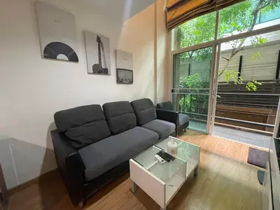 a living room with a black couch and a table at Loft at sanambinnam in Ban Bang Talat