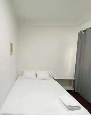 a bed with white sheets and pillows in a room at xx GO INN Siriraj BKK โกอินน์ ศิริราช in Bangkok Noi