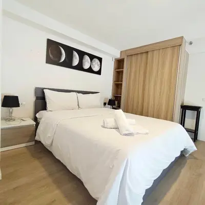 a bedroom with a large white bed with two clocks on the wall at BTS onnut loft quiet room Netflix Rooftop bar in Bangkok