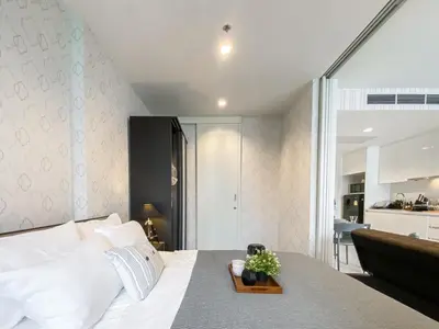 a bedroom with a large white bed with a table at Modern High-Rise 1BR - Ultra Fast Wifi - Sathorn in Bangkok