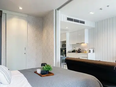 a bedroom with a bed and a room with a kitchen at Modern High-Rise 1BR - Ultra Fast Wifi - Sathorn in Bangkok