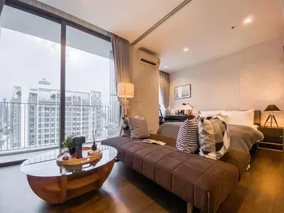 a living room with a couch and a large window at Modern High-Rise 1BR - Ultra Fast Wifi - Sathorn in Bangkok