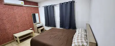 a bedroom with a bed and a brick wall at Ber Ben House in Bang Su