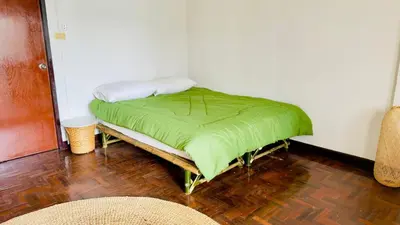 a bed in a room with a green blanket on it at Creative Bangkok Bed in Sathani Bang Khen