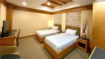 a hotel room with two beds and a television at The Rich Hotel Rama 5 in Ban Bang Phai