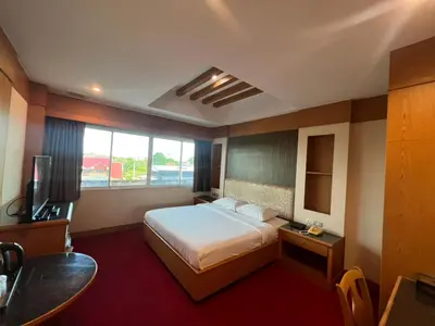 a hotel room with a bed and a television at The Rich Hotel Rama 5 in Ban Bang Phai