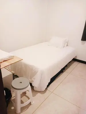 a white bed with a stool in a room at xx GO INN Asiatique BKK - โกอินน์ เอเชียทีค เจริญกรุง in Godown