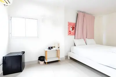a white bedroom with a bed and a window at XX Oh My Nap - BTS Nana โอ้ มาย แนป ซอยนานา in Bangkok