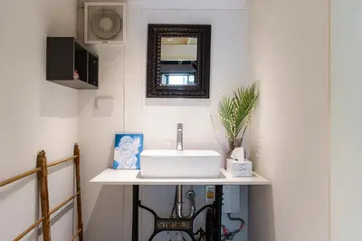 a bathroom with a sink and a mirror at Non Inn Entire Historic 5 Bedroom Riverside Shophouse near ICONSIAM for Families and Groups in Bang Rak
