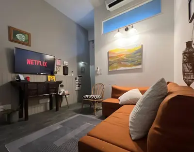 a living room with a couch and a television at Non Inn The Post Spacious King Room with Sofa Bed and Living Area near Riverside and ICONSIAM in Bang Rak