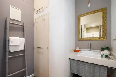 a bathroom with a sink and a mirror at Non Inn The Post Spacious King Room with Sofa Bed and Living Area near Riverside and ICONSIAM in Bang Rak