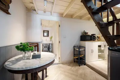 a room with a table and a kitchen with a staircase at Non Inn The Diamond Artisan and Barber 4 Bedroom Riverside Retreat with King and Twin Rooms in Bang Rak