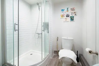 a white bathroom with a shower and a toilet at Non Inn The Diamond Artisan and Barber 4 Bedroom Riverside Retreat with King and Twin Rooms in Bang Rak