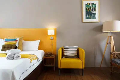 a hotel room with a bed and a yellow chair at Non Inn The Post and Barber 3 Bedroom Riverside Shophouse with King and Twin Rooms in Bang Rak