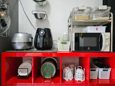 a red shelf with a microwave and other kitchen items at Kuma House Sukhumvit in Bangkok