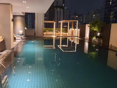 a swimming pool at night with a city skyline at Kuma House Sukhumvit in Bangkok