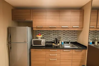 a kitchen with wooden cabinets and a stainless steel refrigerator at Modern 2 Bed Executive Unit - 5min to Nana BTS in Bangkok