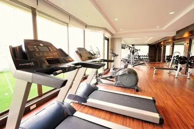 a gym with cardio equipment in a room with windows at Modern 2 Bed Executive Unit - 5min to Nana BTS in Bangkok