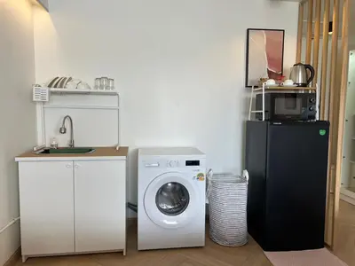 a kitchen with a washing machine and a microwave at Lazy House at Impact Muangthong in Thung Si Kan