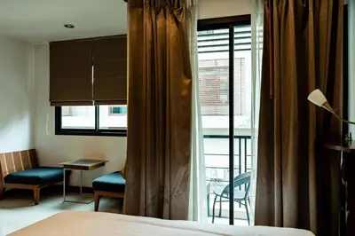 a bedroom with a bed and a window with a balcony at XX YON INN Sukhumvit 4 Bangkok - BTS Nana in Bang Kapi
