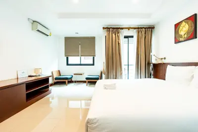 a hotel room with a white bed and a desk at XX YON INN Sukhumvit 4 Bangkok - BTS Nana in Bang Kapi