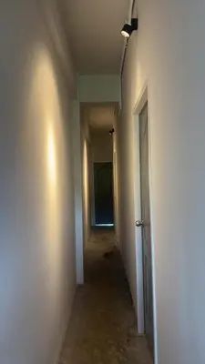an empty hallway with a white wall and a door at Capricorn hostel Yaowarat in Chinatown