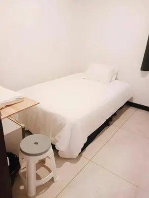 a white bed with a stool next to a table at XX GO INN Asiatique Bangkok โก อินน์ เอเชียทีค เจริญกรุง in Bangkok