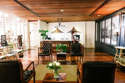 a man standing in a lobby with chairs and tables at Nanda Heritage Hotel in Bangkok