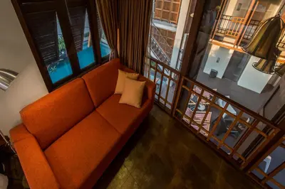 an orange couch in a room with a balcony at Nanda Heritage Hotel in Bangkok