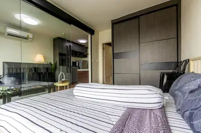 a bedroom with a large white bed with a glass wall at TC Contel At True Digital Park in Amphoe Phra Khanong