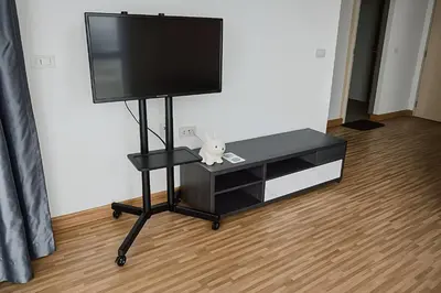 a flat screen tv on a black stand with a stuffed animal at Laid back at IRIS Westgate Bangkok-Nonthaburi in Ban Bang Phai
