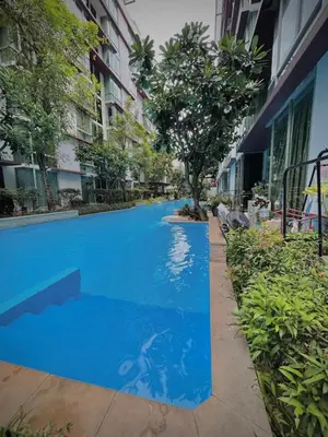 a blue swimming pool in the middle of a building at Modern Condo with Full Amenities Bangkok in Sathani Ban Hua Mak