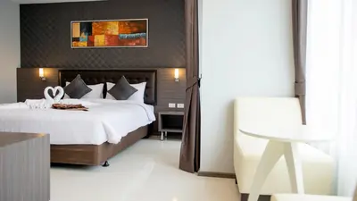 a bedroom with a large bed and a chair at Picnic Hotel Bangkok - Rang Nam in Bangkok