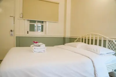 a bed with white sheets and pillows and a window at White Lodge Hotel Bangkok in Bangkok