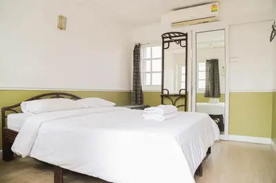 a bedroom with two beds and a mirror at White Lodge Hotel Bangkok in Bangkok