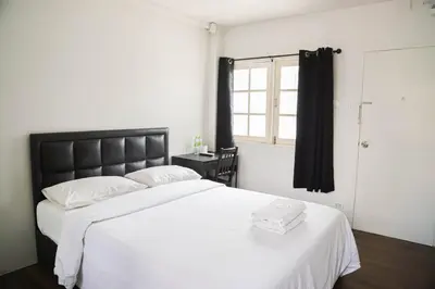 a bedroom with a large white bed and a window at White Lodge Hotel Bangkok in Bangkok