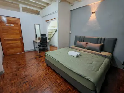 a bedroom with a bed and a desk and a door at Charoen Nakhon 48 House in Godown