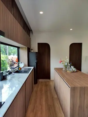 a kitchen with wooden cabinets and a counter top at Chobjai Hostelry - Chaw Cher Home at Bang Kra Jao in Bang Krasop