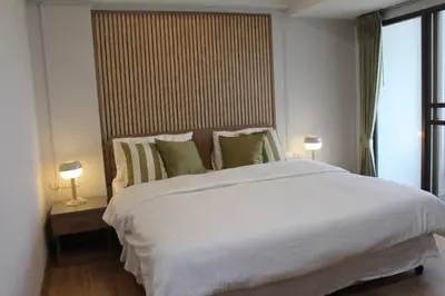 a bedroom with a large white bed with two lamps at Bangkok Place Apartment - EKAMAI BTS in Bangkok