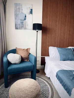 a bedroom with a blue chair next to a bed at Happy House T8 in Thung Si Kan
