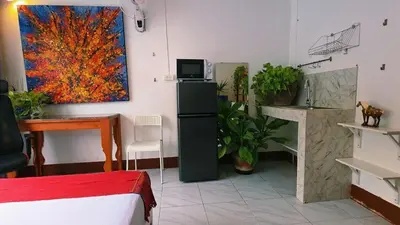 a room with a bed and a desk and a painting at Lumphini Perfect Escape Sunny Rooftop EnSuite in Bangkok