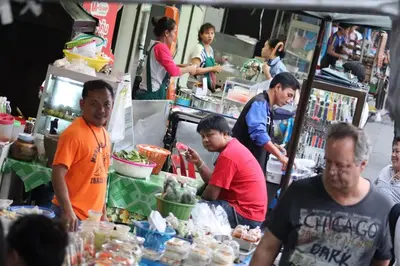 a group of people standing around a food stand at Lumphini Perfect Escape Sunny Rooftop EnSuite in Bangkok