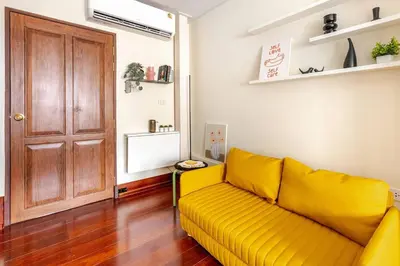a yellow couch in a living room with a door at Nueng Rana 232 Corner view 1BR Duplex 3beds / 2B in Samphanthawong