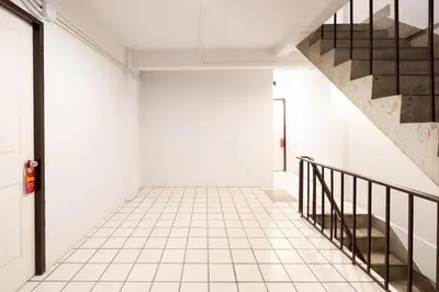 a hallway with a staircase and a white tiled floor at XX Mitr Inn Khaosan Street - มิตร อินน์ ตรอกข้าวสาร in Bangkok