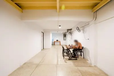 a man sitting at a table in an empty room at XX Mitr Inn Khaosan Street - มิตร อินน์ ตรอกข้าวสาร in Bangkok