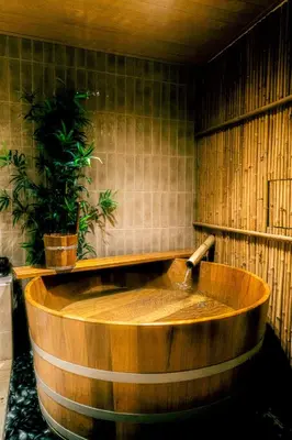 a wooden tub with a faucet in a bathroom at Hakotel in Bang Rak