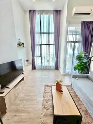 a large living room with purple curtains and a television at Modiz Modiza Sukhumvit R3 in Bangkok