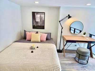 a bedroom with a bed with a desk and a mirror at Modiz Modiza Sukhumvit R3 in Bangkok